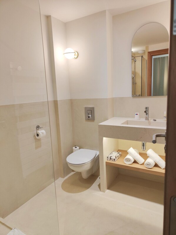 Un baño moderno con inodoro, lavabo y ducha.