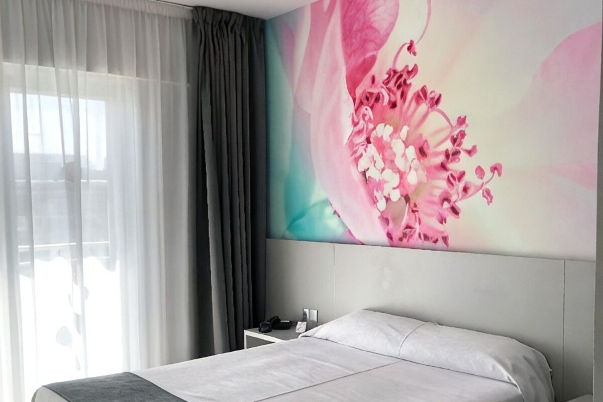 Une chambre d’hôtel moderne avec un grand lit, une table de chevet et une œuvre d’art accrochée au mur.