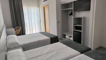 Ein Hotelzimmer mit zwei Betten, einem Kleiderschrank und einem Sessel.