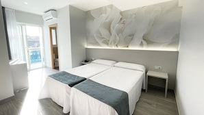 Un dormitorio moderno con una cama grande, dos mesitas de noche y un aire acondicionado de pared.