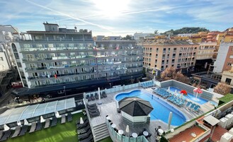 Un hotel con piscina en la azotea, varios balcones y un comedor.