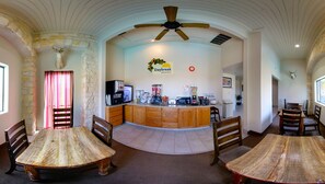 A breakfast area with a stone wall, wooden tables, and a ceiling fan. - Days Inn & Suites by Wyndham Llano (Llano)