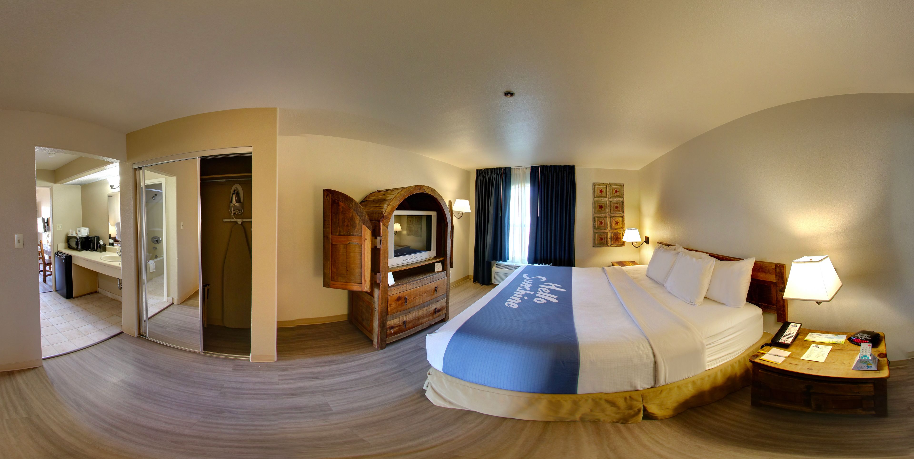 Una habitación de hotel con una cama, un escritorio con lámpara, un televisor y un armario.
