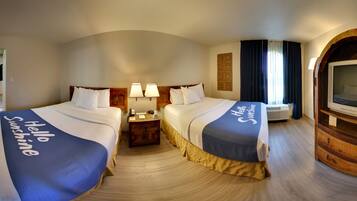 Quarto de hotel com duas camas, uma televisão e um espelho.