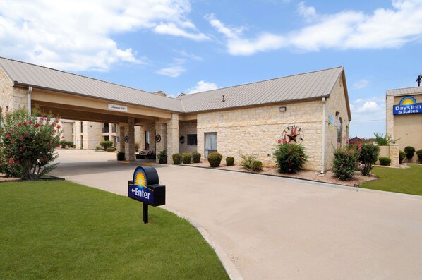 A Days Inn & Suites with a stone facade, a covered entrance, and a clear sky. - Days Inn & Suites by Wyndham Llano (Llano)