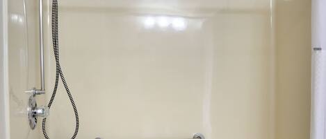 A walk-in shower with a grab bar, a bench, and a towel rack.