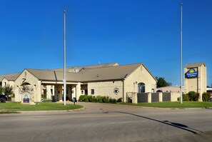 A Days Inn & Suites building with a stone facade, a large sign, and a parking lot. - Days Inn & Suites by Wyndham Llano (Llano)