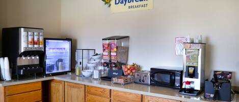 A breakfast area with a refrigerator, coffee machine, microwave, toaster, and cereal dispensers.