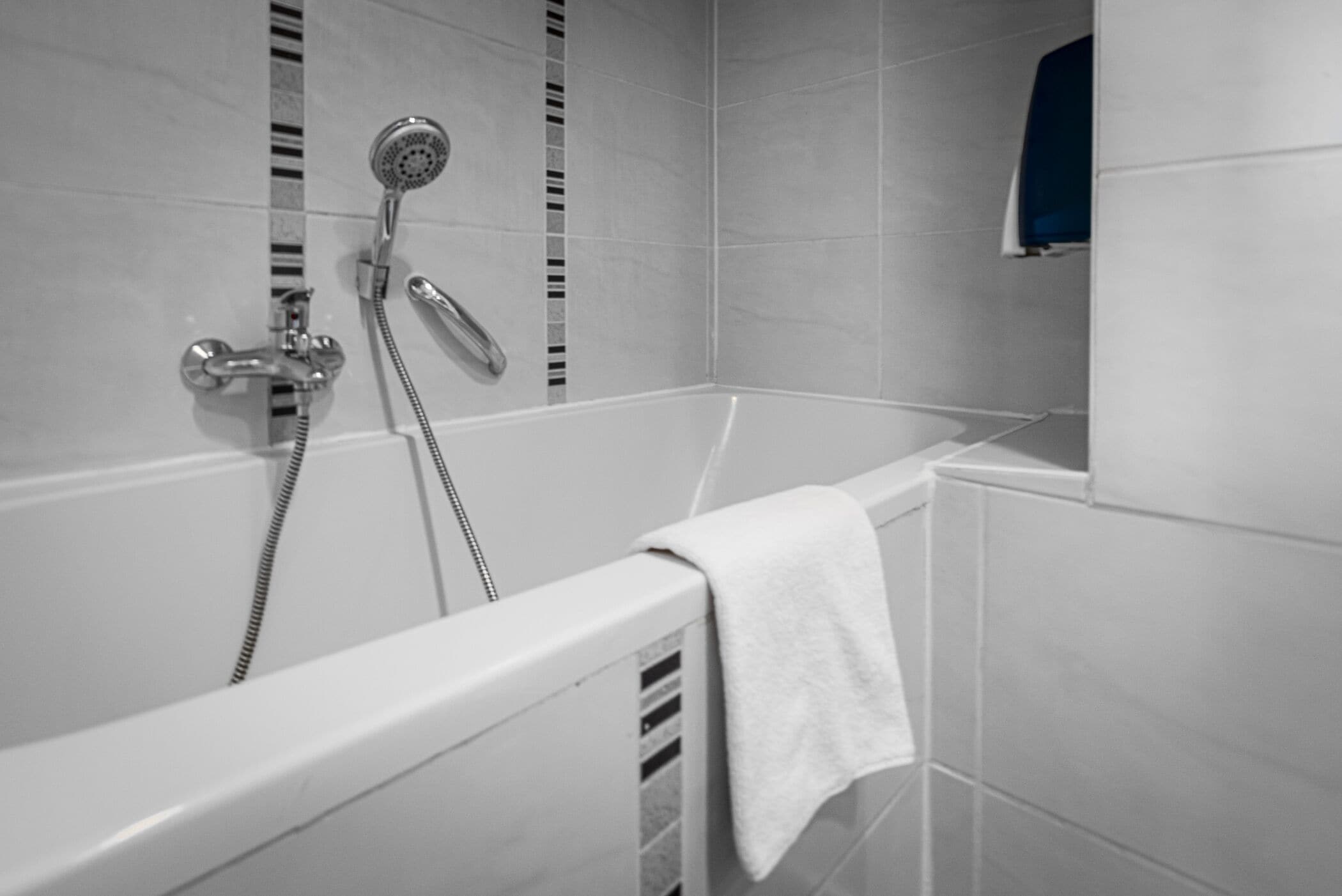 Un baño moderno con una bañera, un cabezal de ducha y una toalla colgada en la pared.