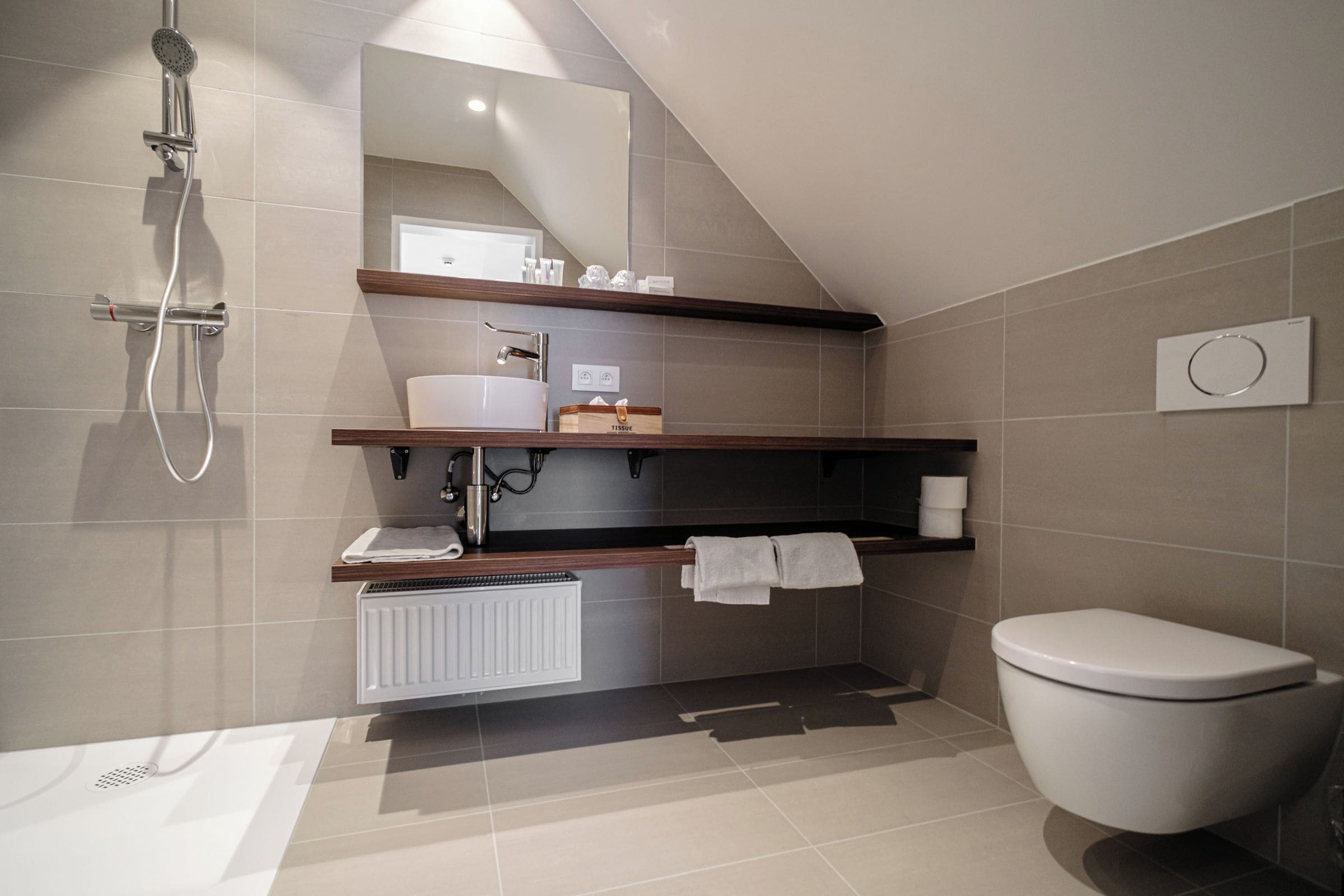 A modern bathroom with a shower, toilet, and a sink with a towel rack.