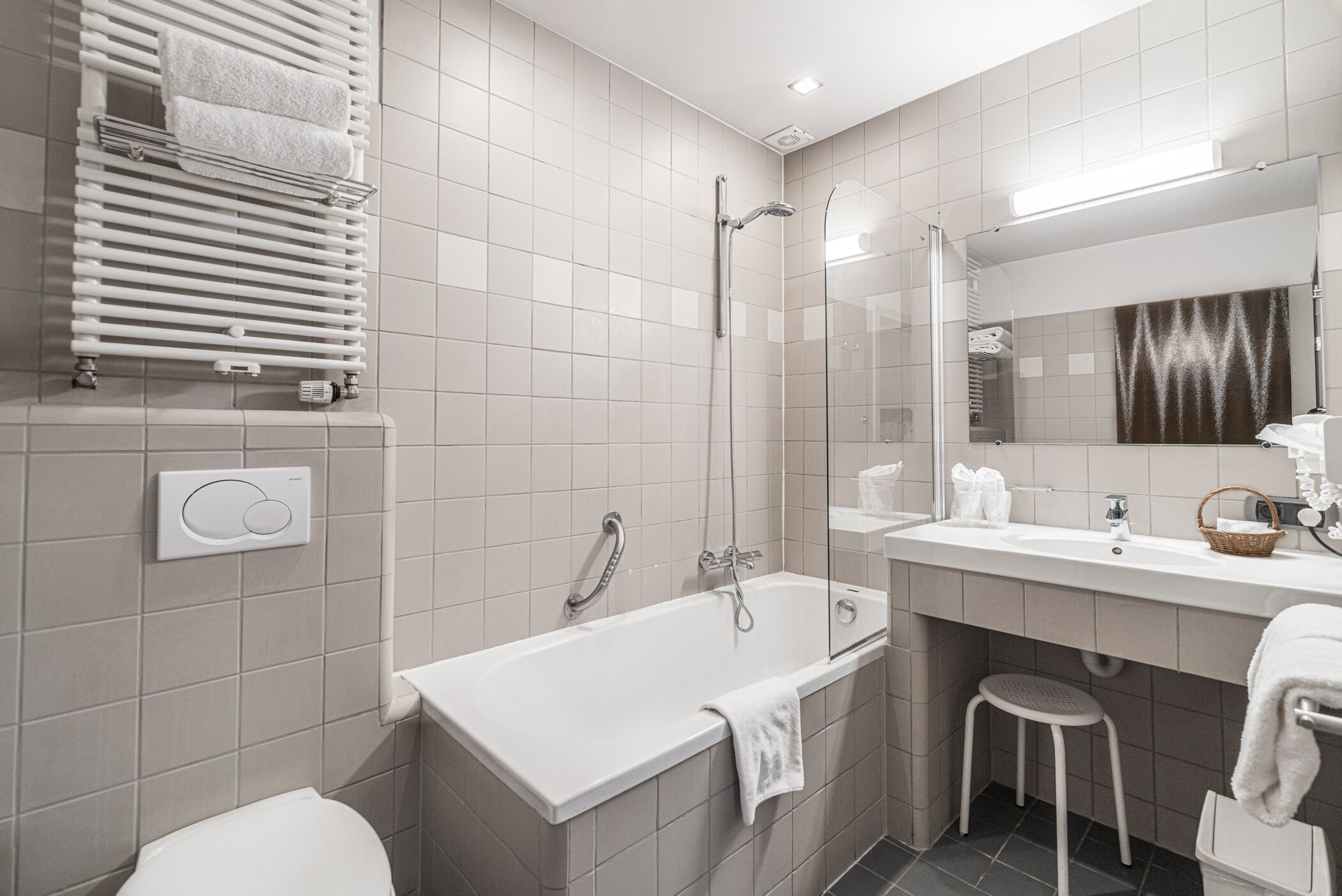 A modern bathroom with a bathtub, shower, toilet, and vanity with a mirror.