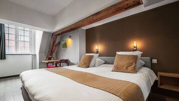 A bedroom with a large bed, two bedside tables, a wooden headboard, a desk, and a chair.