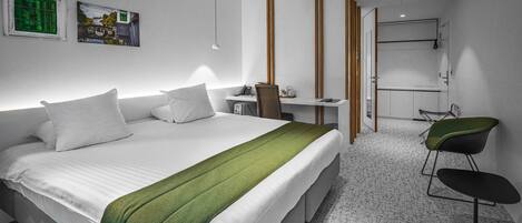 Una habitación de hotel moderna con una cama grande, un escritorio, una silla y una zona de ducha.