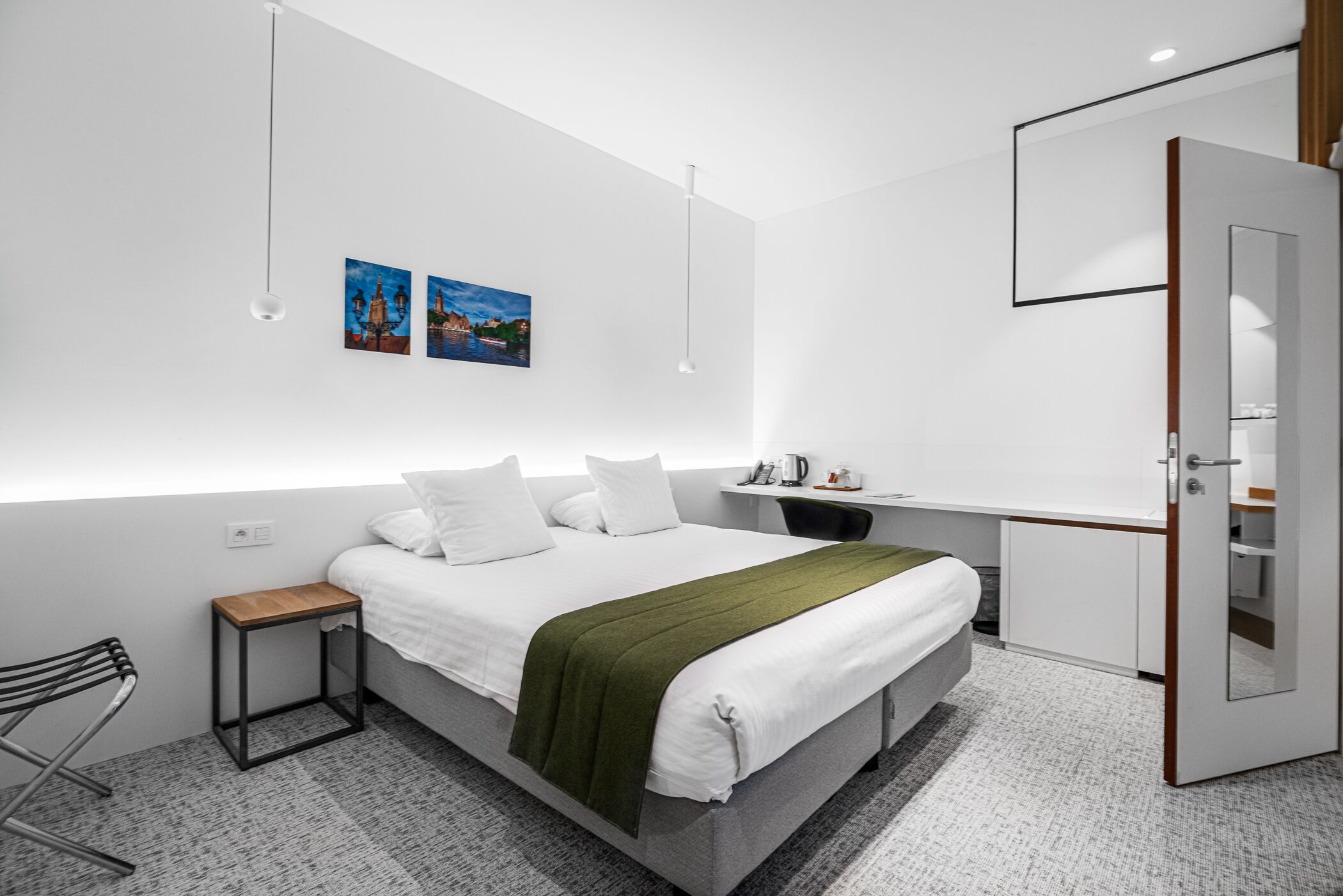Un dormitorio moderno con una cama grande, mesitas de noche, un escritorio y un armario.