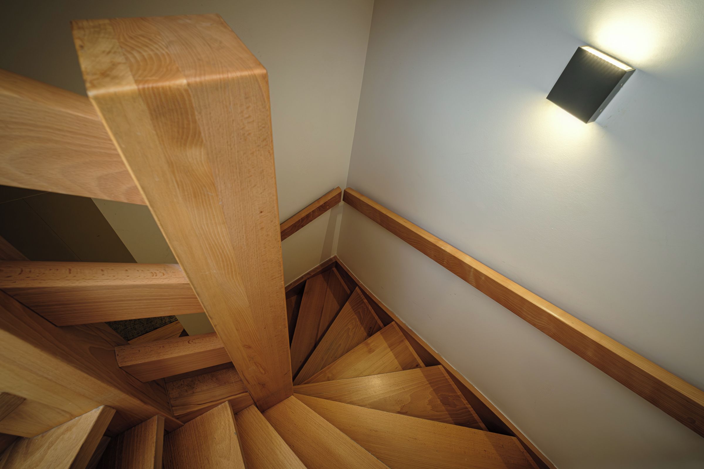 A wooden staircase with a light fixture on the wall.
