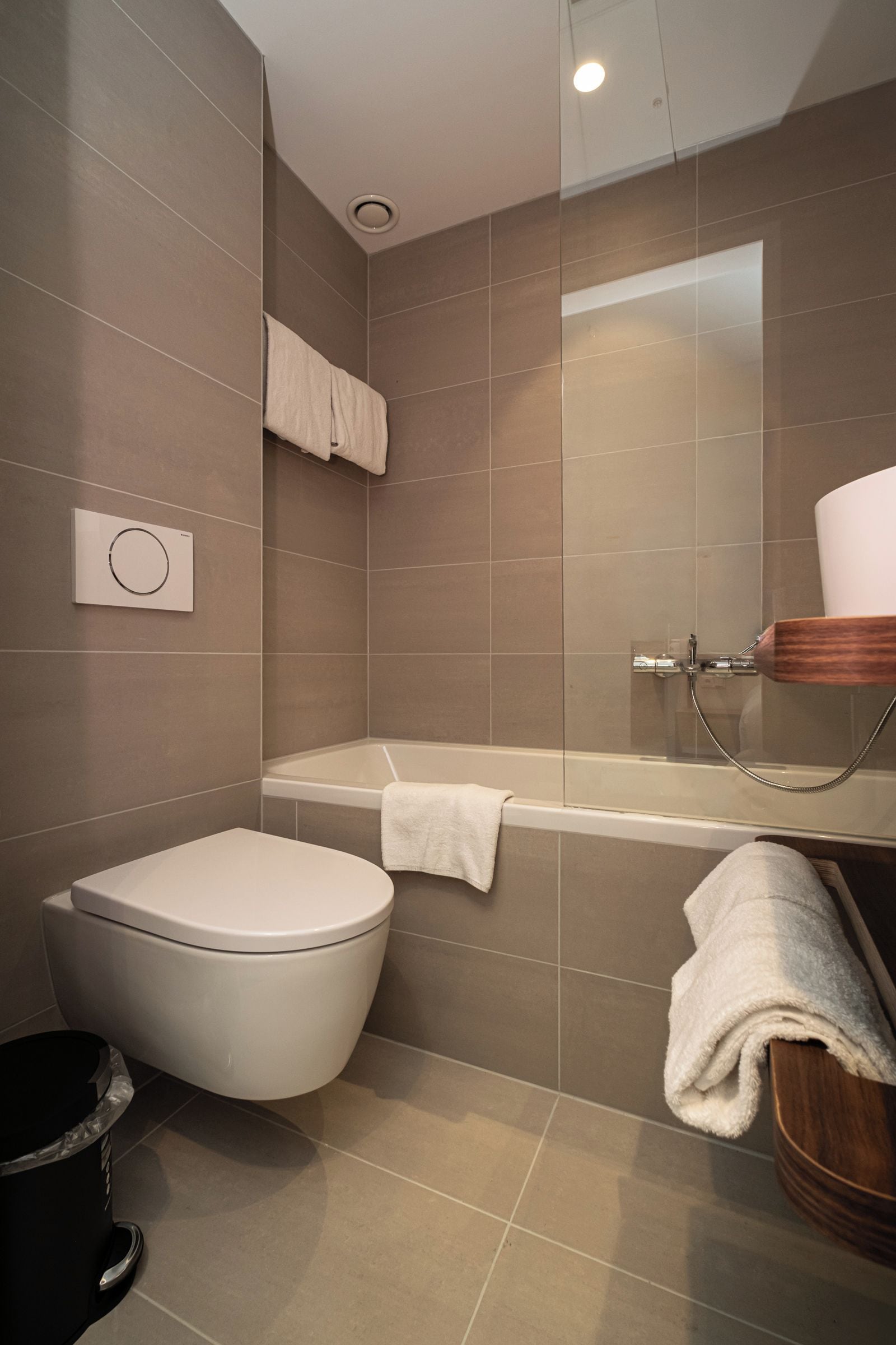 A modern bathroom with a toilet, bathtub, and shower.