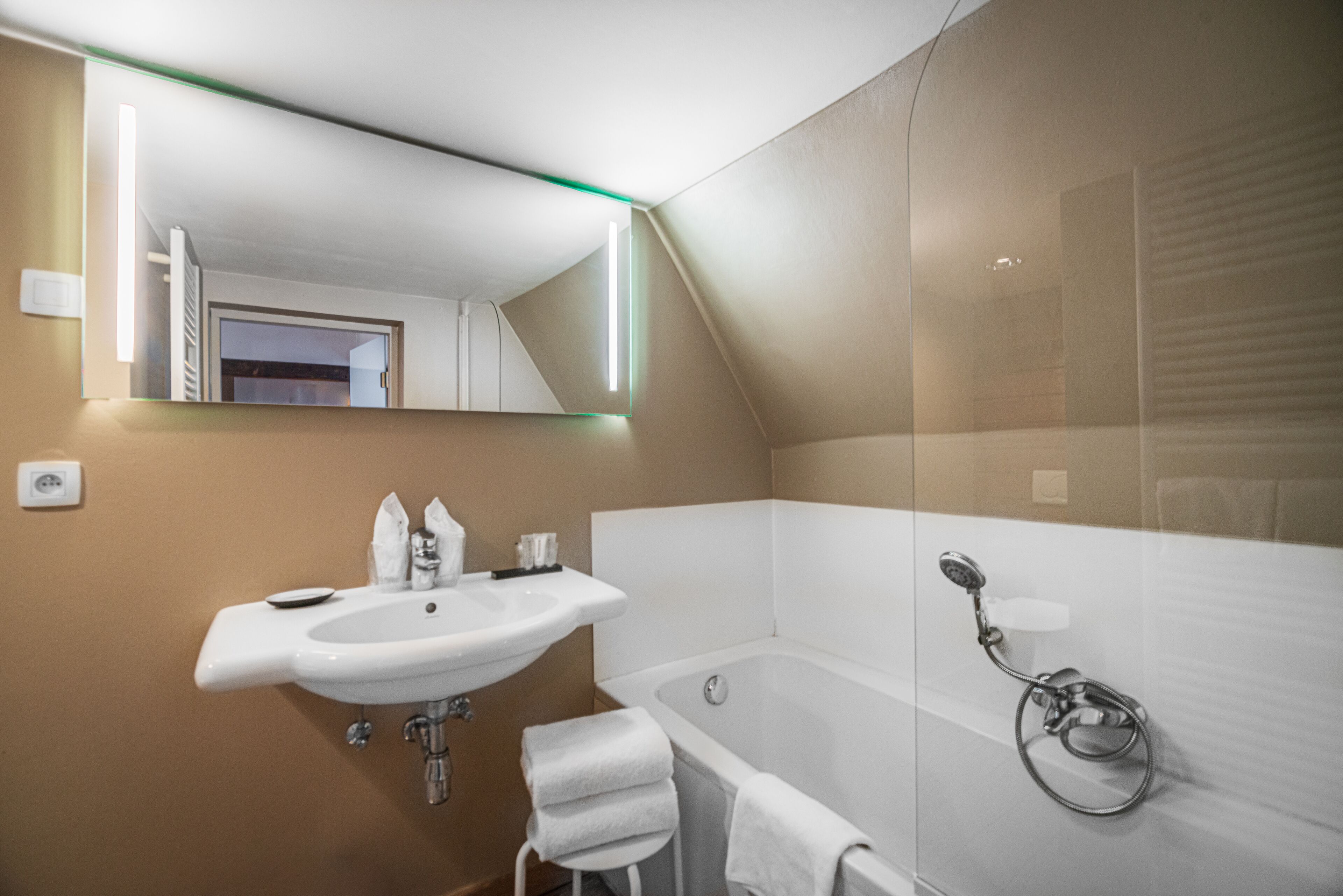 A modern bathroom with a white sink, a bathtub, and a glass shower enclosure.