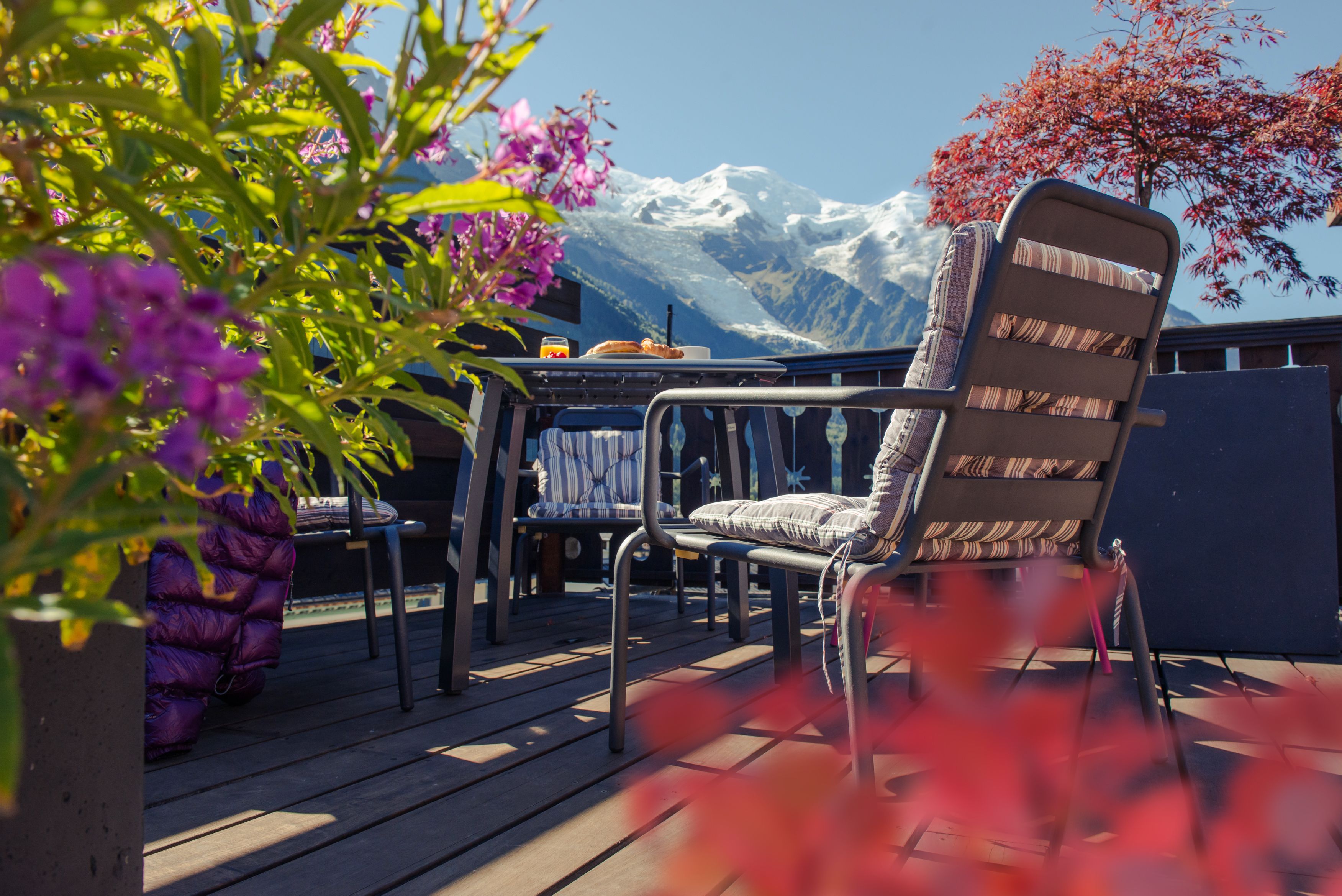 A deck with outdoor furniture, a table, and a chair with a cushion.