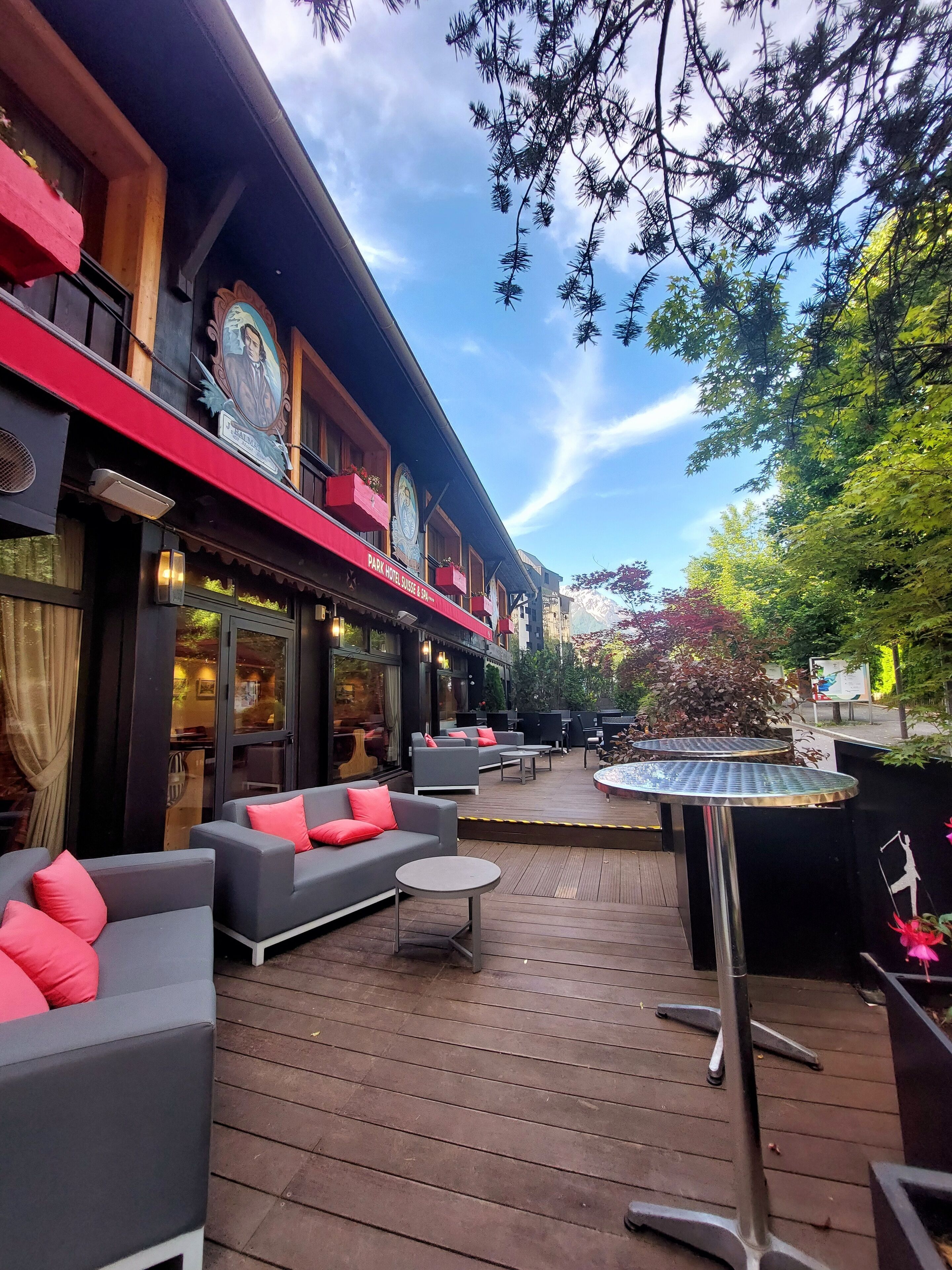 A hotel patio with outdoor seating, a wooden deck, and a view of the surrounding trees.
