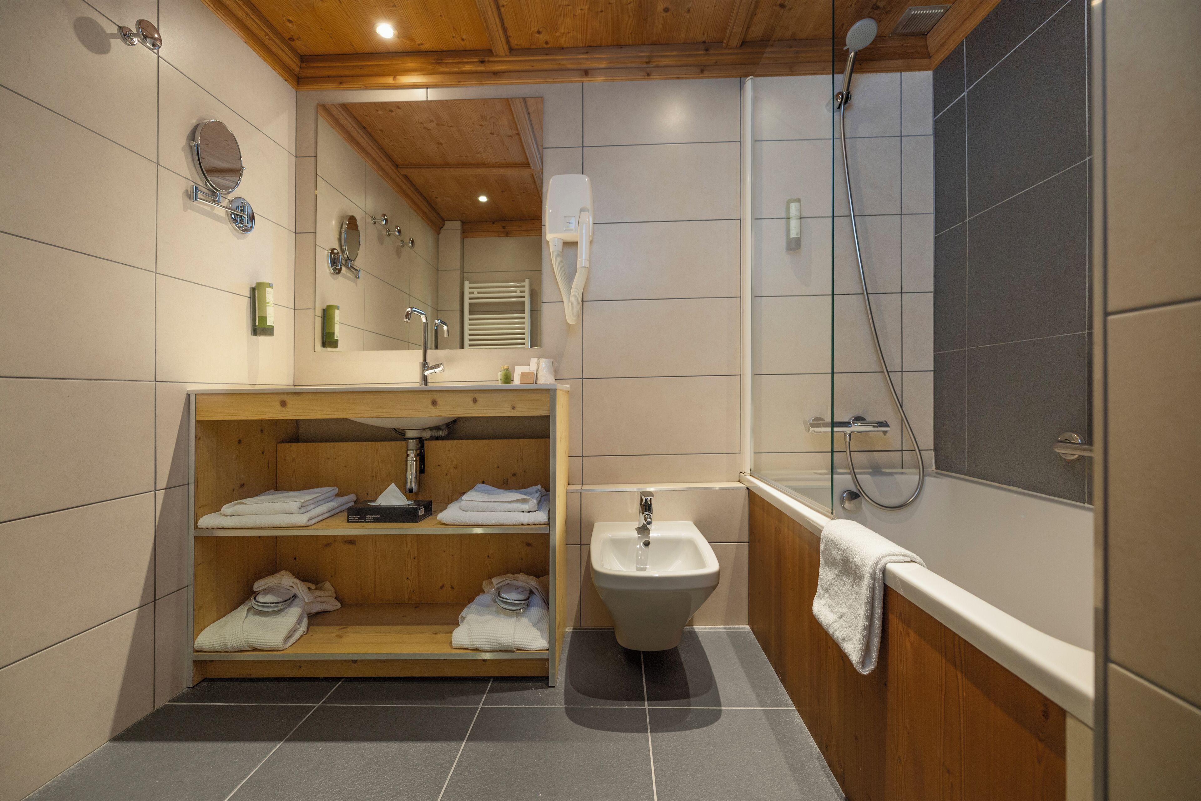 Een moderne badkamer met een houten wastafel, een toiletbril, een bad en een douche.