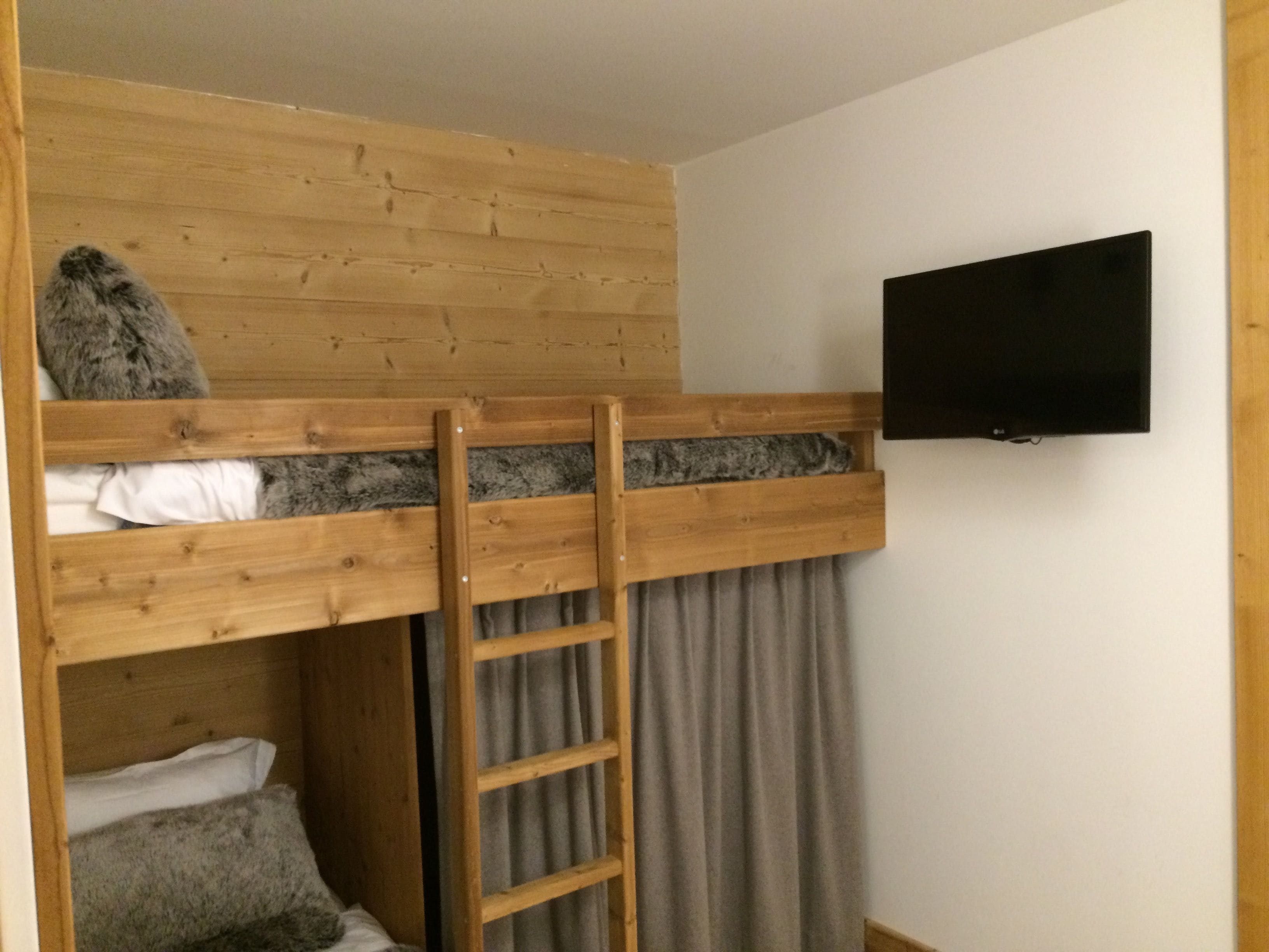 Een stapelbed met een televisie die aan de muur erboven is bevestigd.