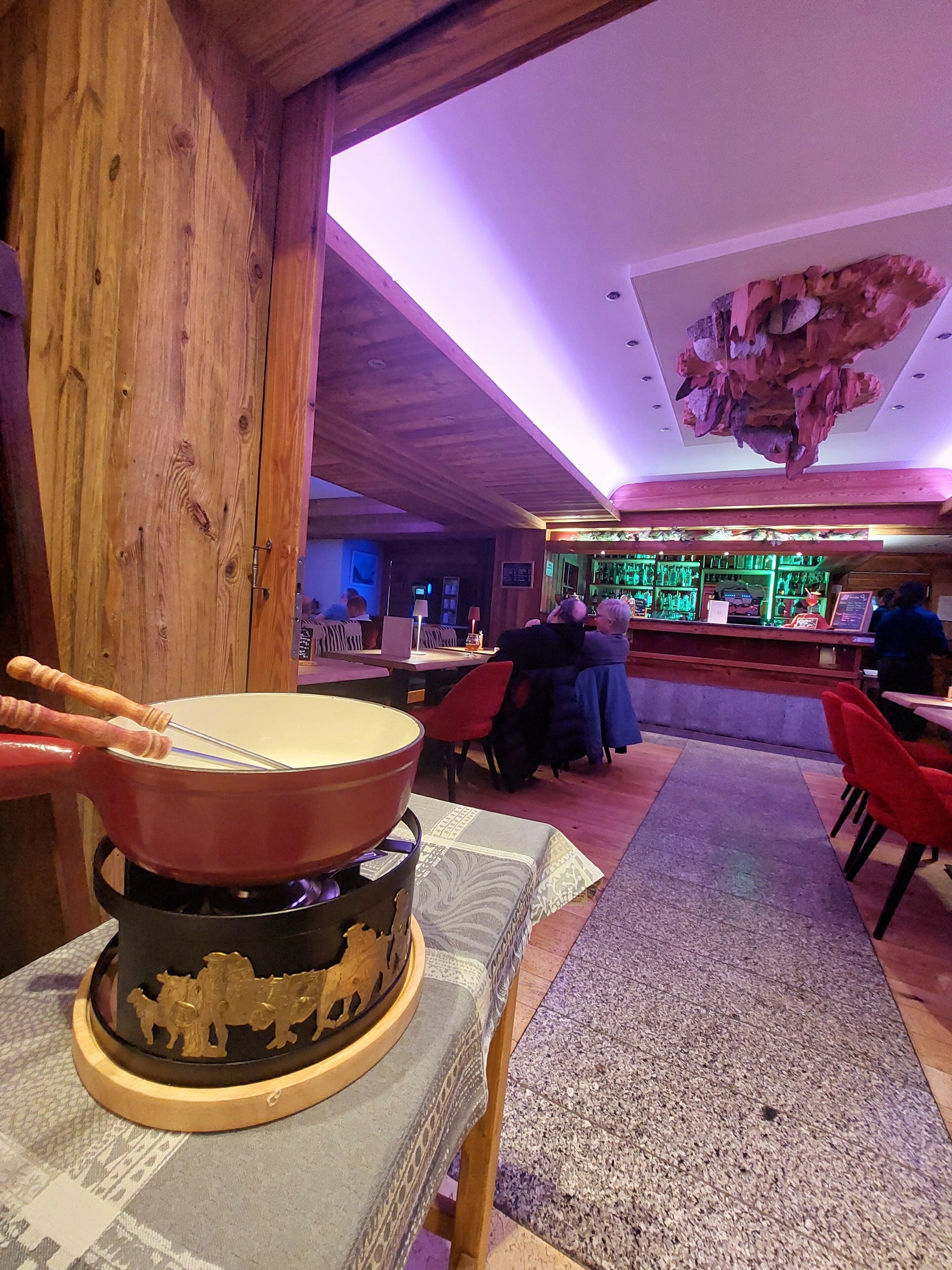 Un ristorante con interni in legno, una zona bar e un soffitto decorativo.