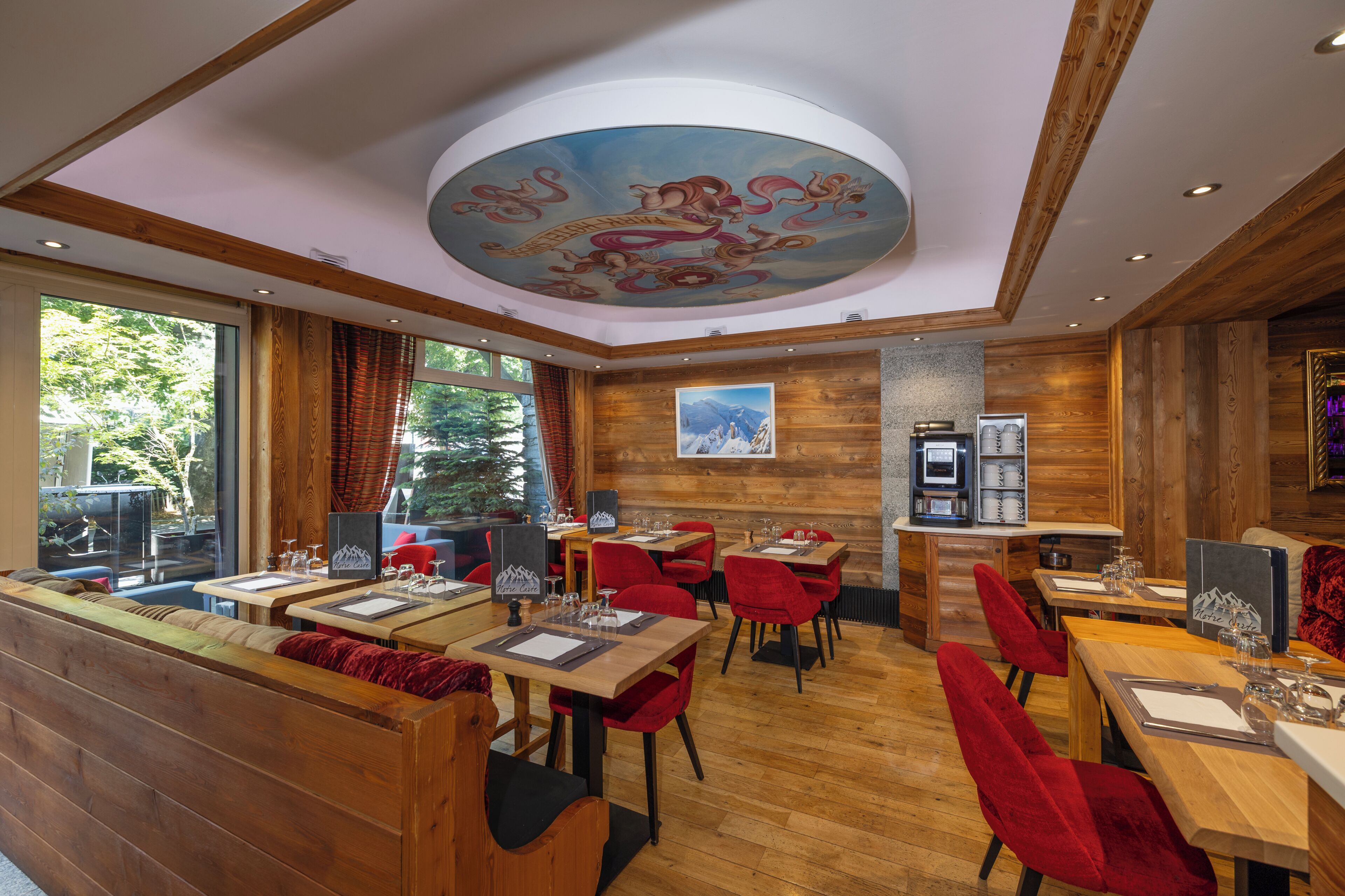 A restaurant with wooden walls, red chairs, and a ceiling mural.