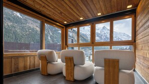 Ein Zimmer mit drei Sofas, großen Fenstern mit Bergblick, Holzboden und Steinböden.