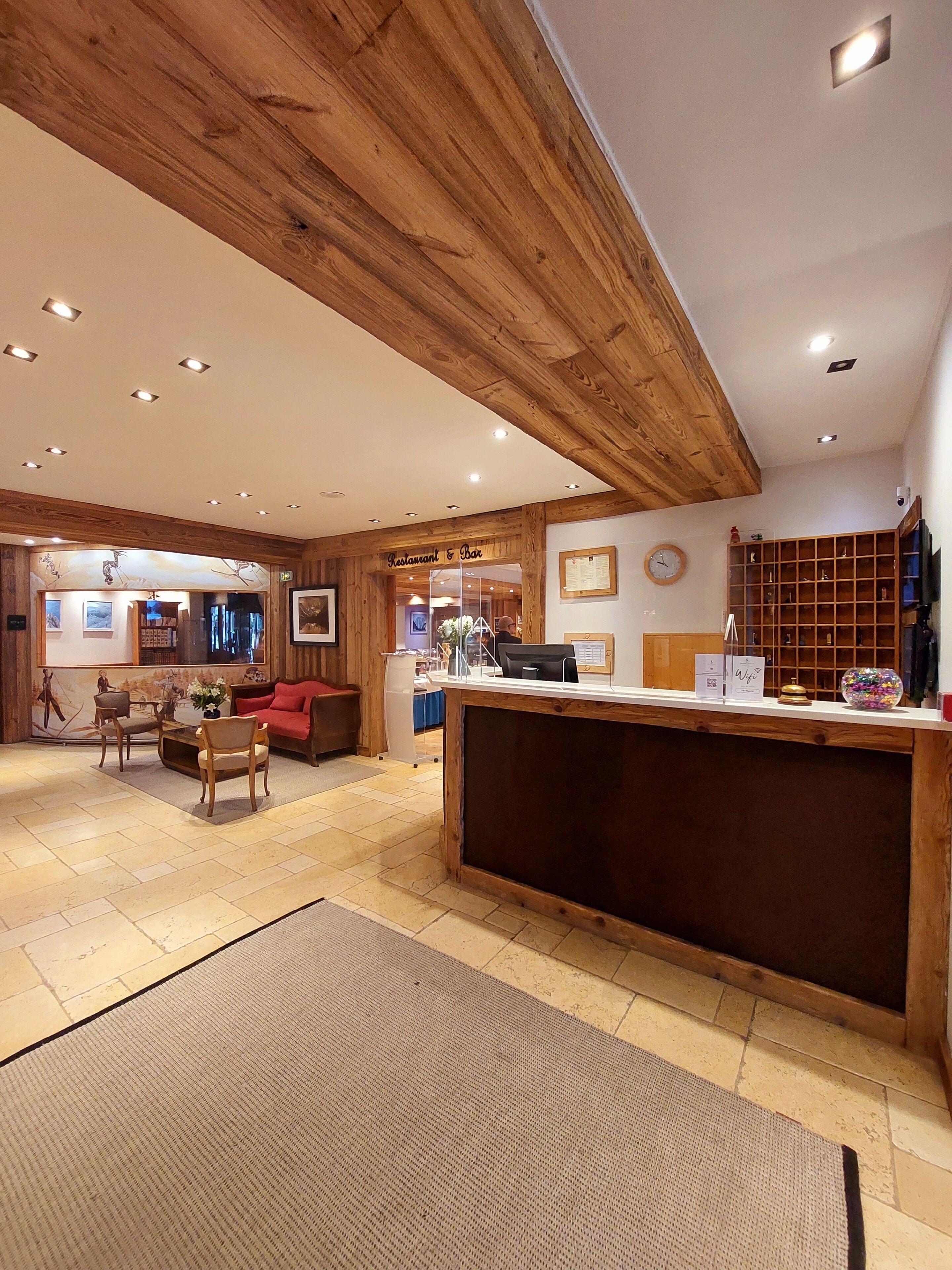A wooden interior with a reception desk, seating area, and a clock on the wall.