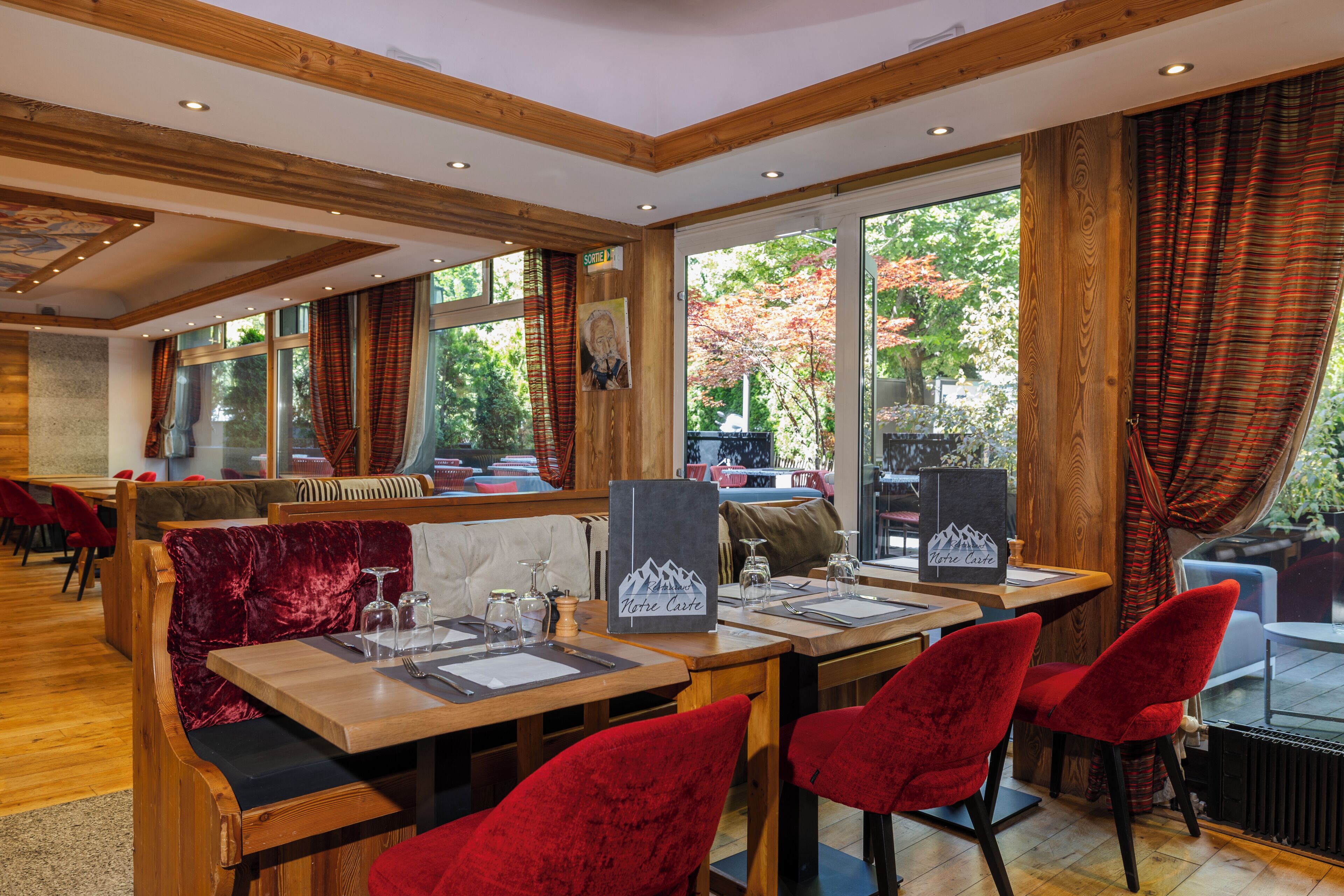A restaurant with wooden tables and red velvet chairs, large windows with curtains, and a sign reading 'Montreux Castle.'