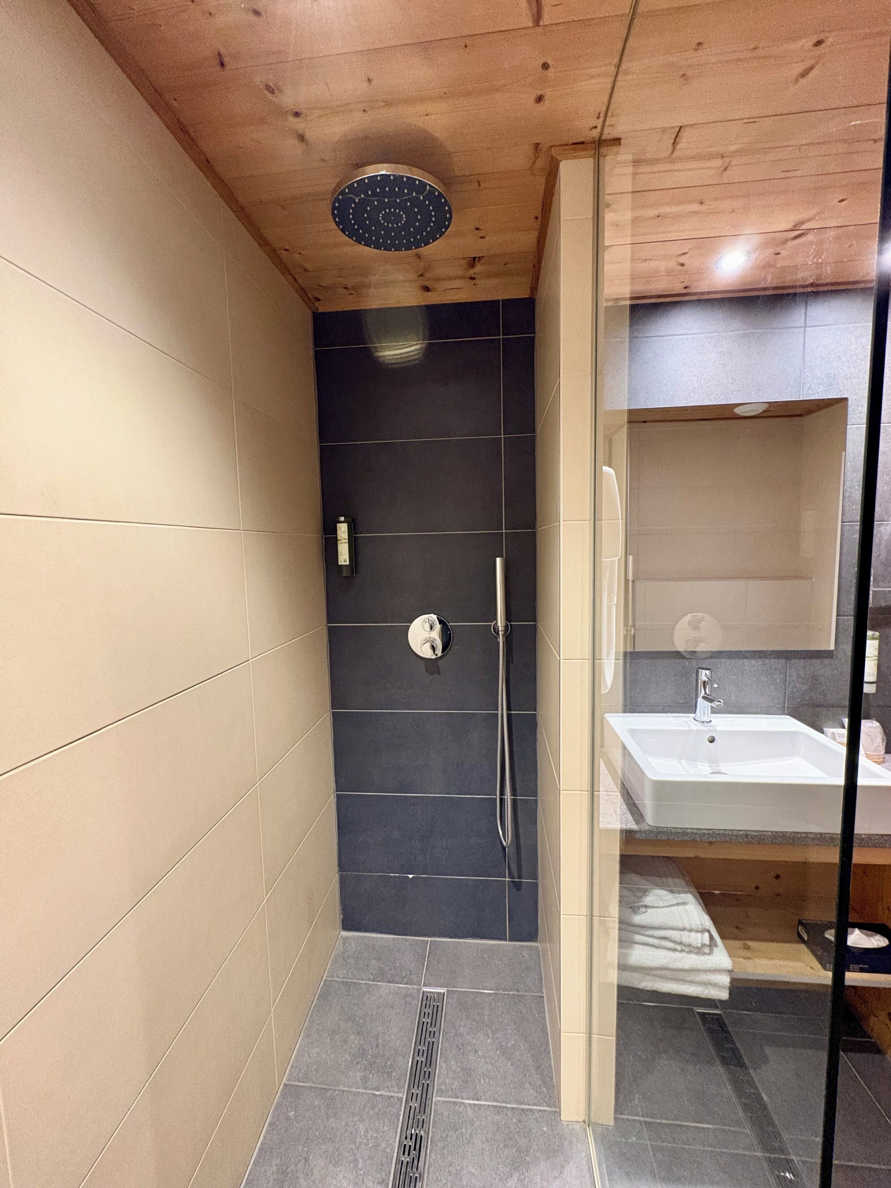 Uma casa de banho moderna com chuveiro, lavatório e divisória de vidro.