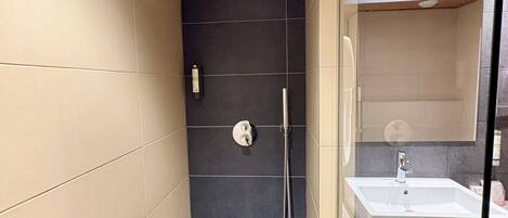 Uma casa de banho moderna com chuveiro, lavatório e divisória de vidro.