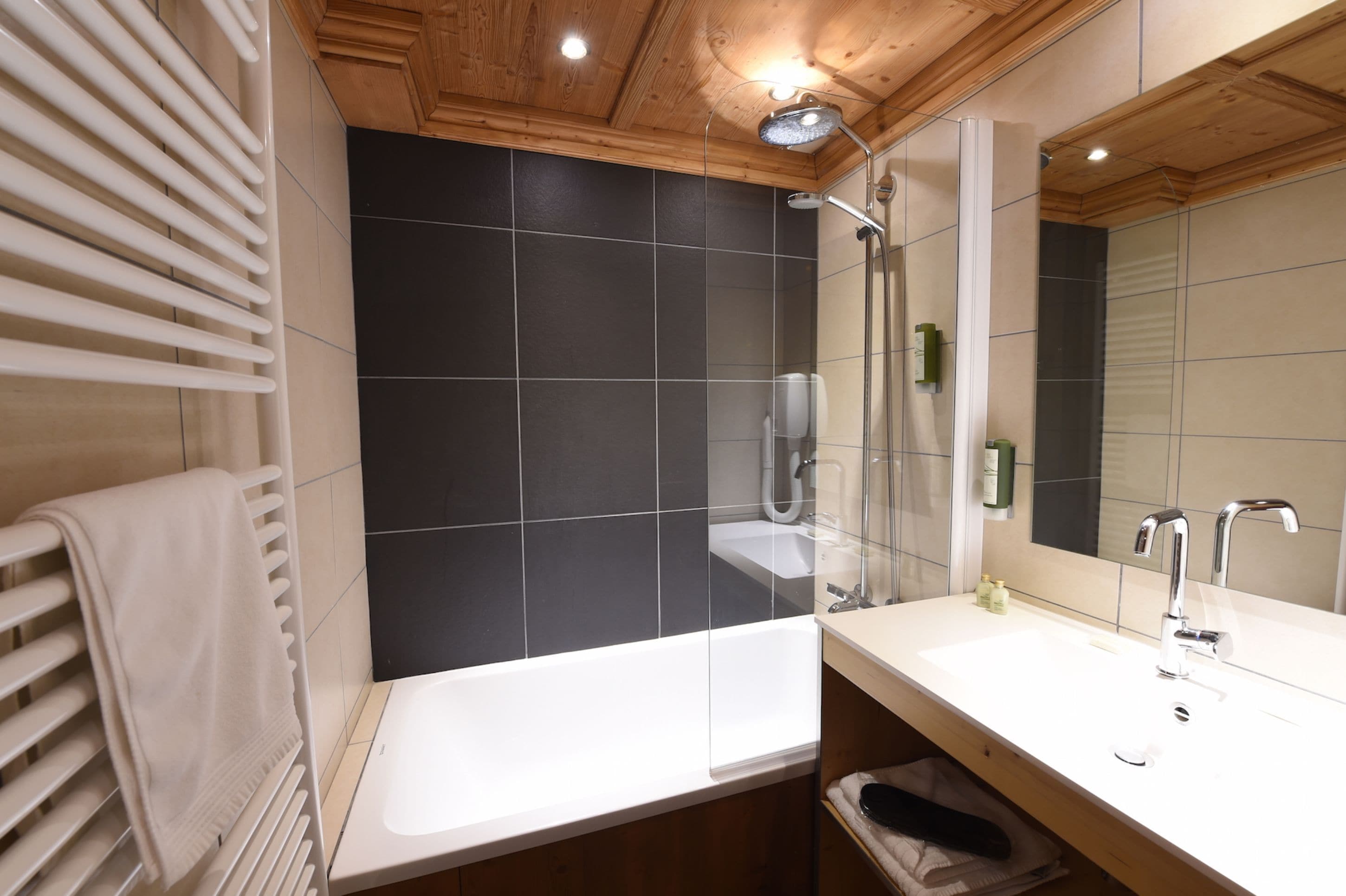 Un baño moderno con bañera, un espejo grande y un perchero para toallas.
