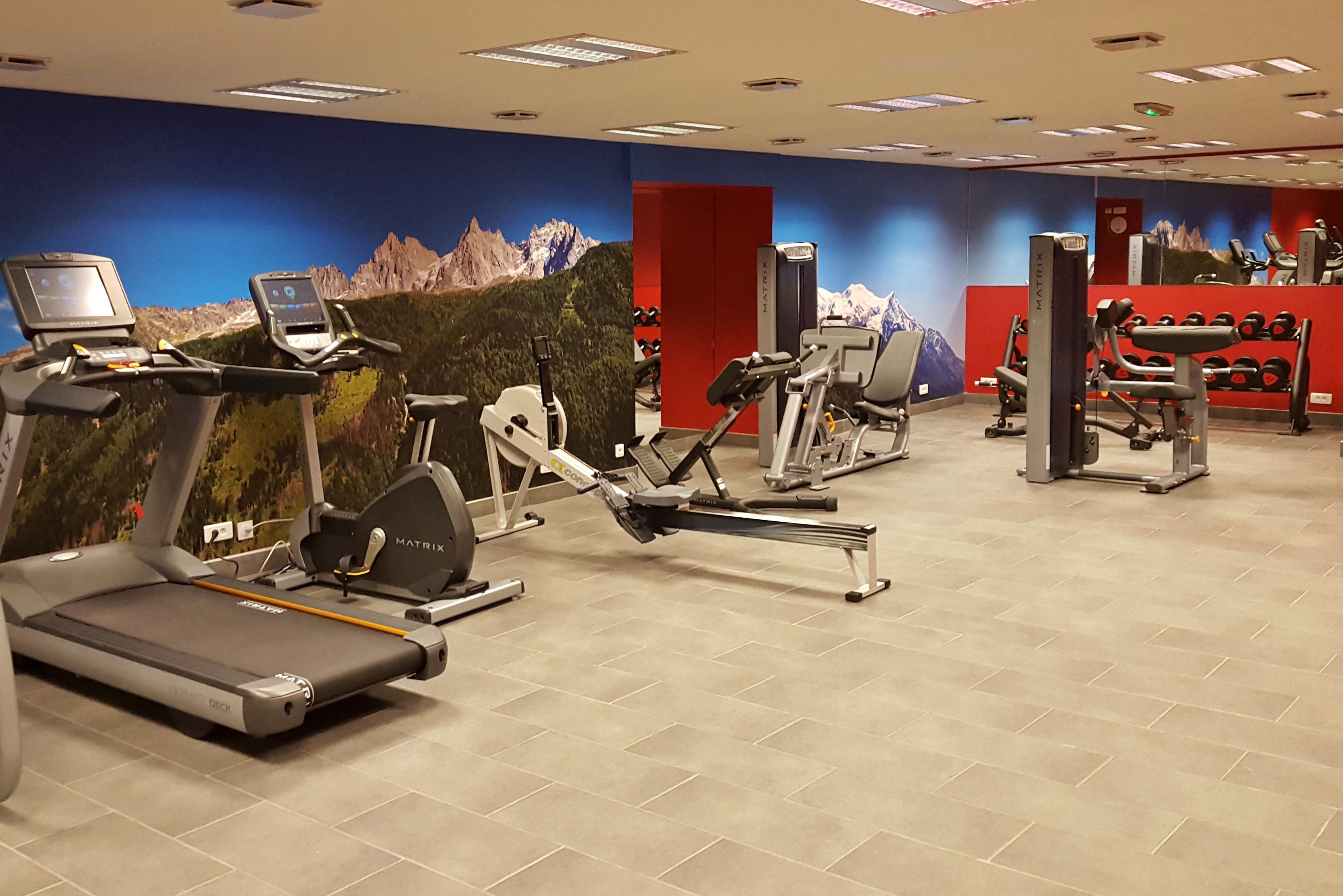 Un gimnasio con cintas de correr, bicicletas estáticas y máquinas de pesas.
