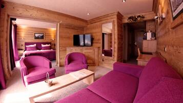 L’intérieur d’une cabane en rondins présente un espace de vie avec des meubles violets, un téléviseur et une cheminée.