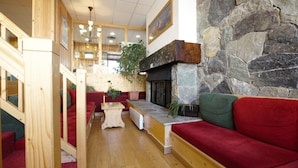 A cozy interior with a stone fireplace, wooden furniture, and a staircase leading to an upper level.