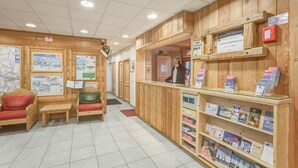 A reception area with wooden paneling, a counter with brochures, and seating with red cushions.
