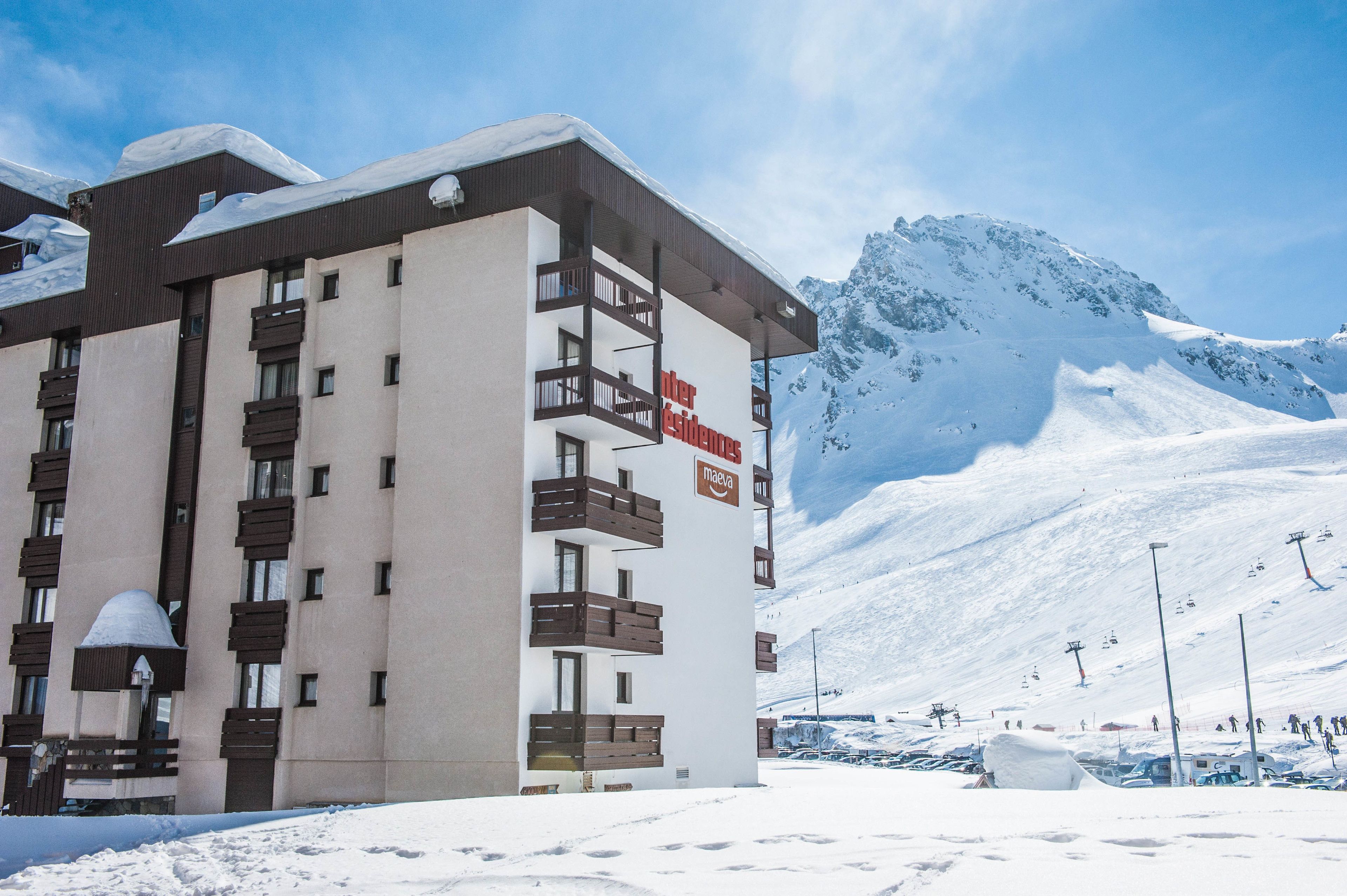 Een hotel met een modern design, met balkons en een piste in de achtergrond.