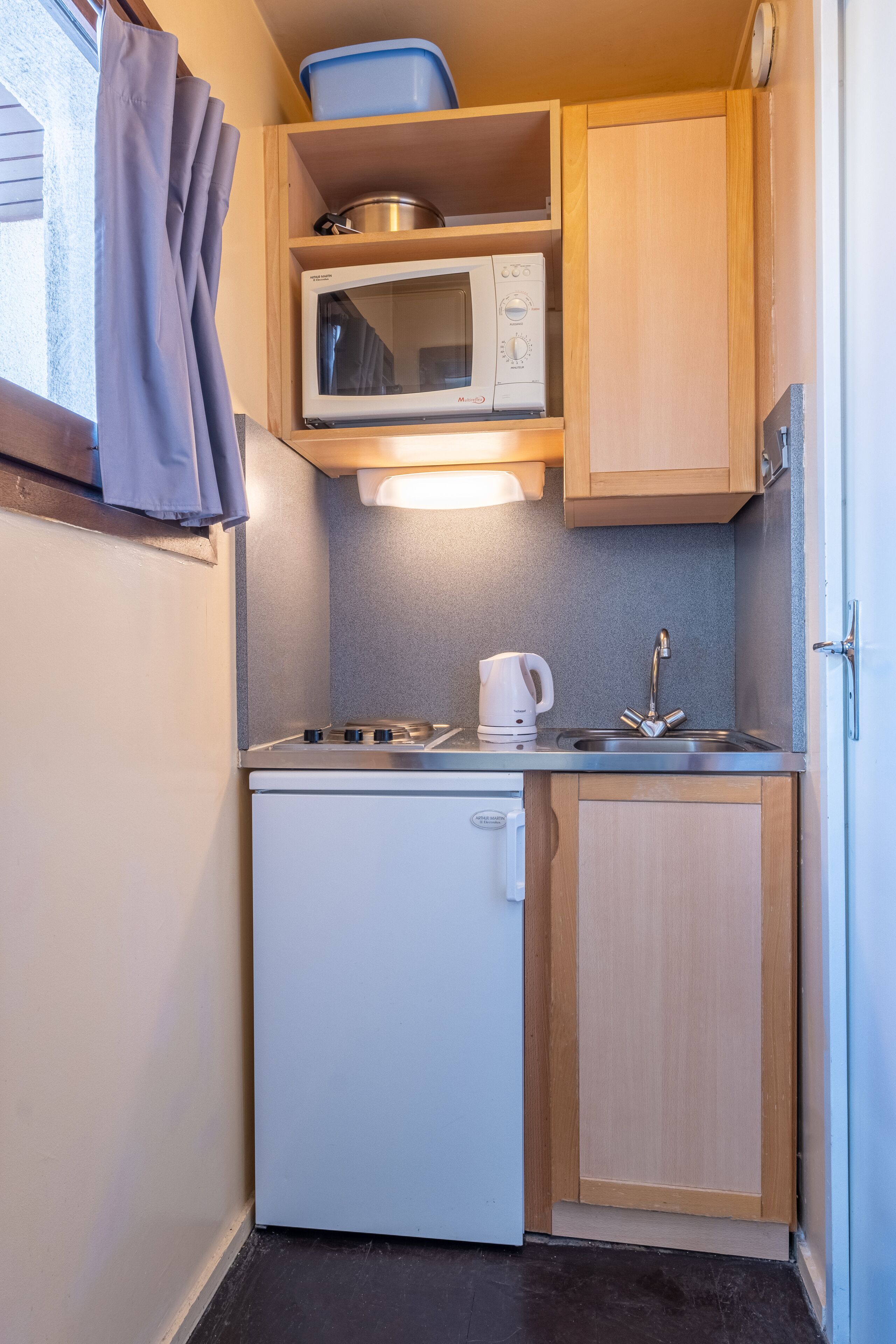 Une petite cuisine équipée d’un four à micro-ondes, d’une cuisinière et d’un évier.
