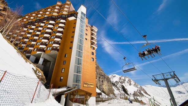 Hotel com vários andares e um teleférico ao fundo.