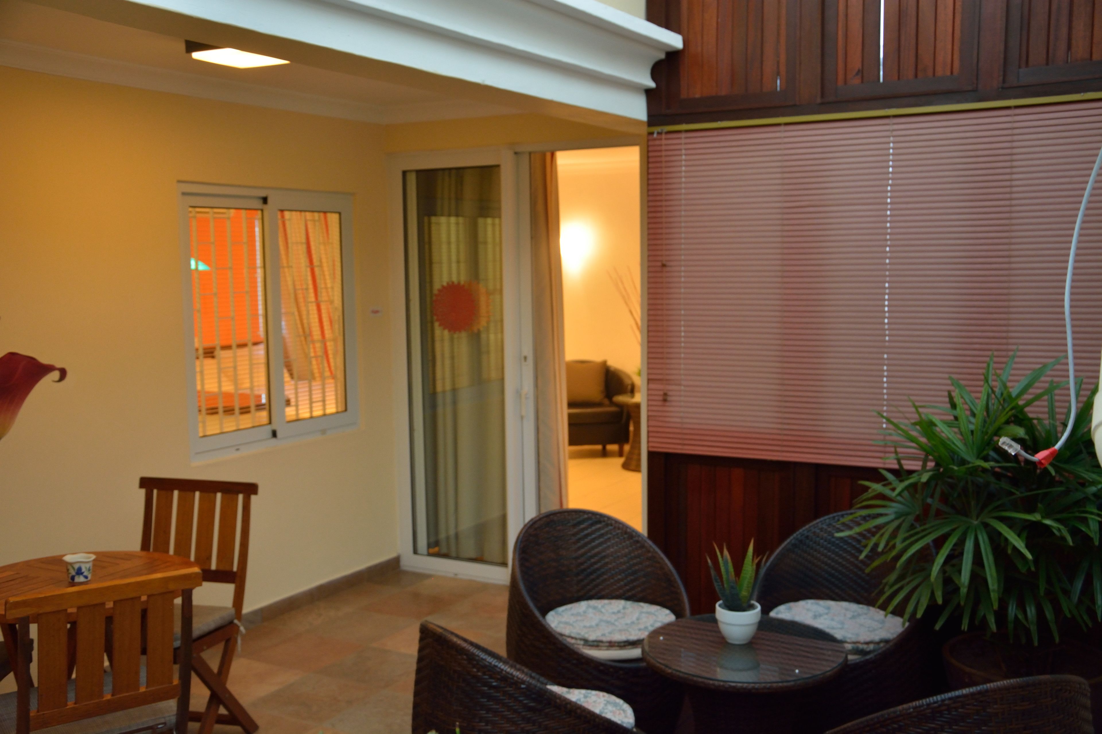 Un patio con mobiliario de mimbre, una mesa y plantas en macetas.