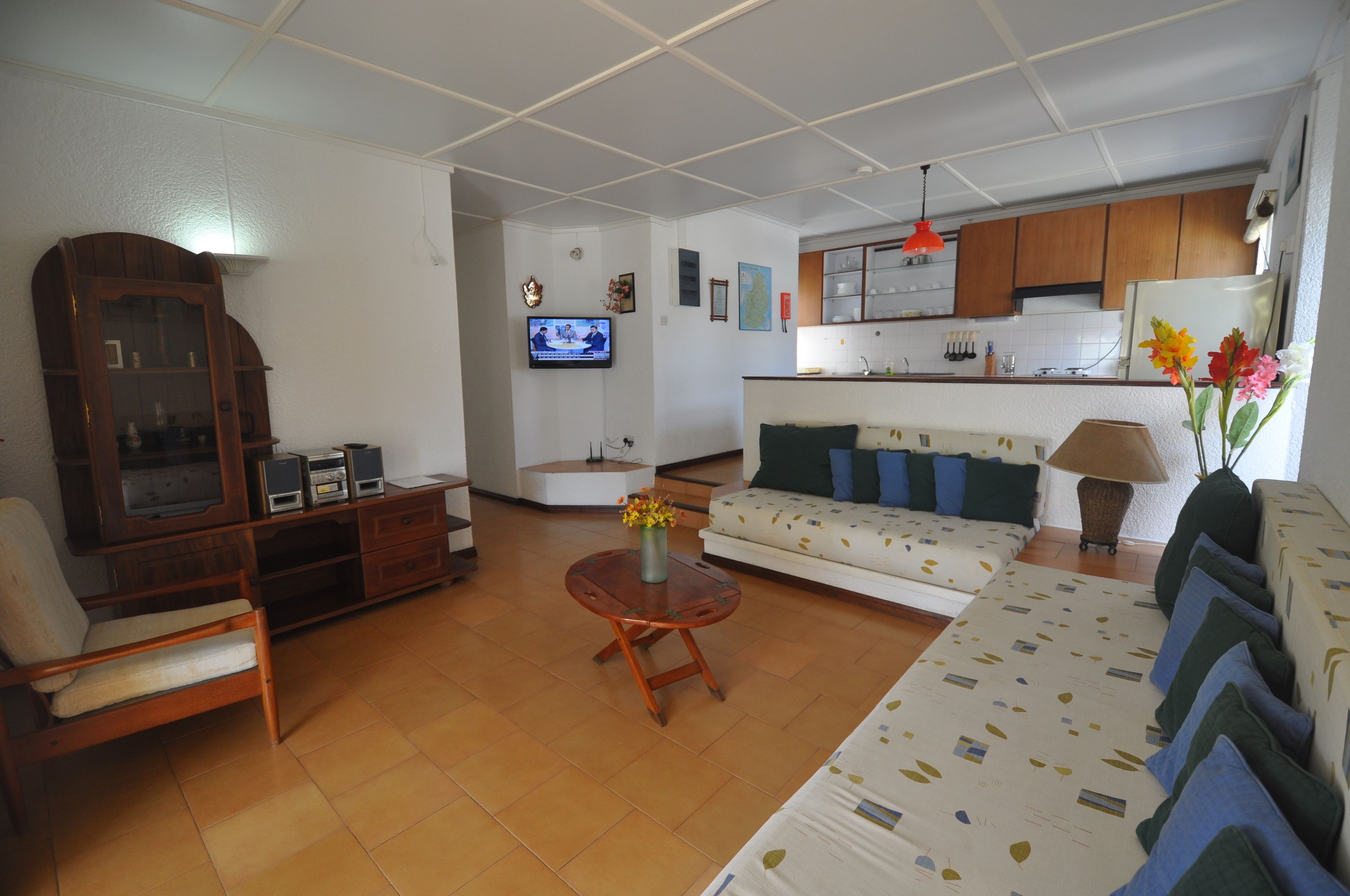 A living room with a sofa, armchair, wooden cabinet, and a television.