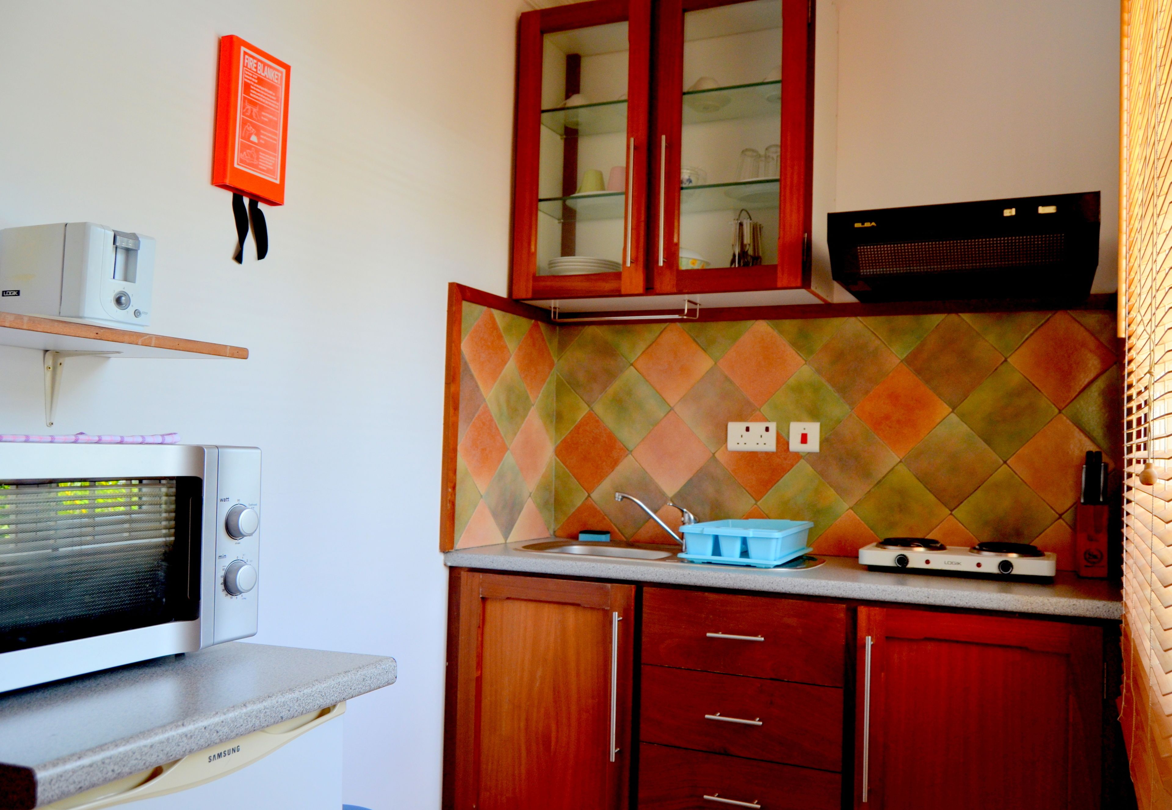 A compact kitchen with a microwave, a gas stove, and wooden cabinets.