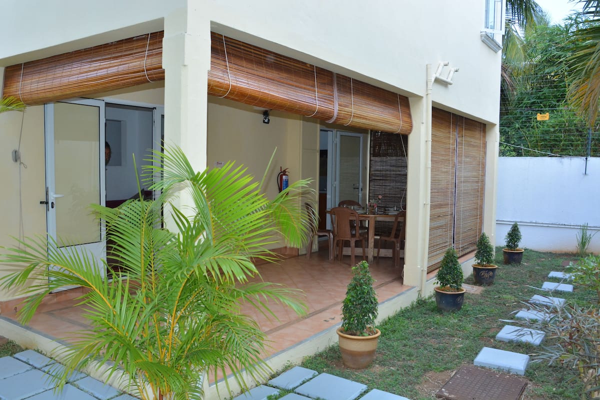 A modern house with a patio, a dining area, and potted plants.