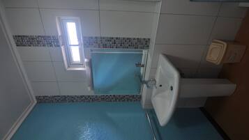 Une salle de bain avec un sol bleu, un lavabo blanc et un miroir.