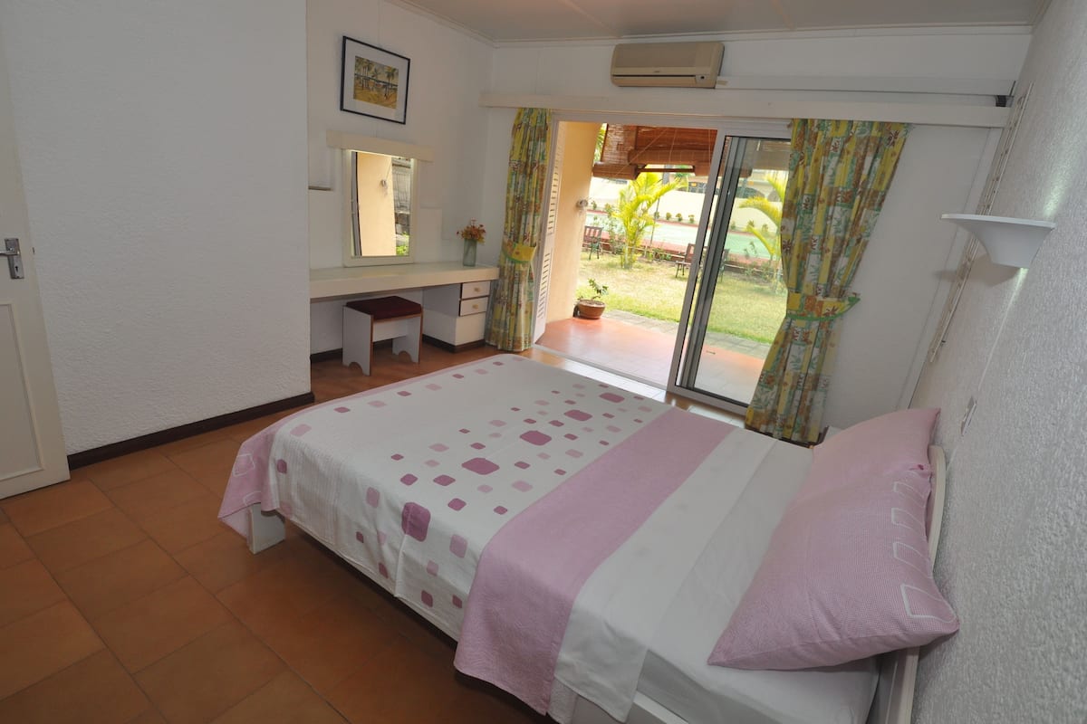 A bedroom with a bed, a desk, and a window with curtains.