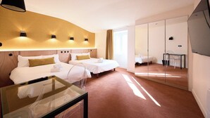 A hotel room with two beds, a glass table, a mirror, and a large window. - Hotel Henri IV (La Rochelle)