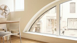 A modern room with a curved window, a dining table, and chairs. - Hotel Henri IV (La Rochelle)