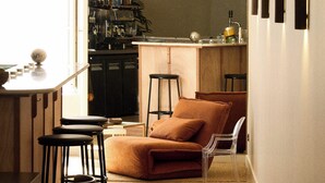 A modern kitchen with bar stools, a sofa, and a clear chair. - Hotel Henri IV (La Rochelle)