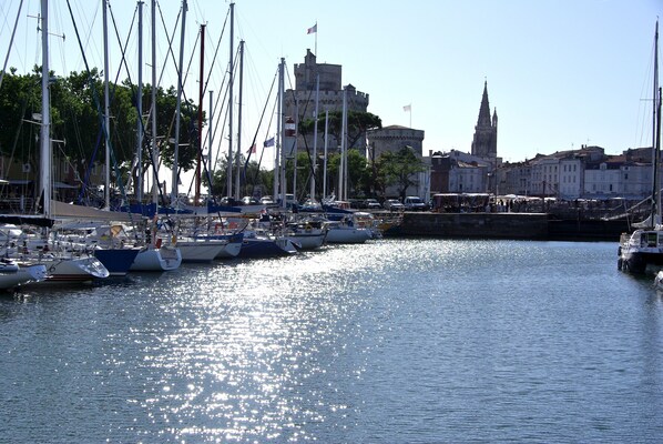 A marina with multiple boats docked, a prominent tower, and a historic building in the background. - Hotel Henri IV (La Rochelle)